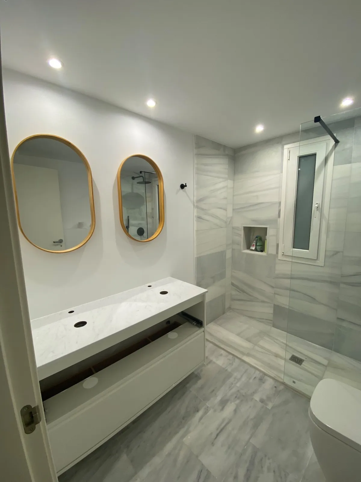 Baño reformado con espejos y mampara a medida